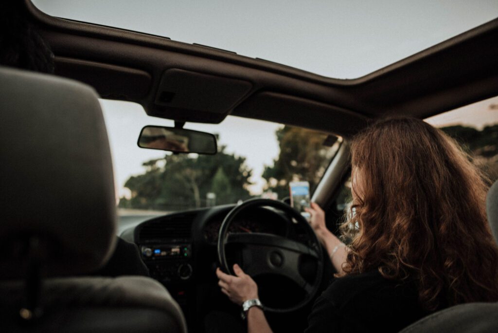 An image of a lady driving while texting, which is a significant road hazard